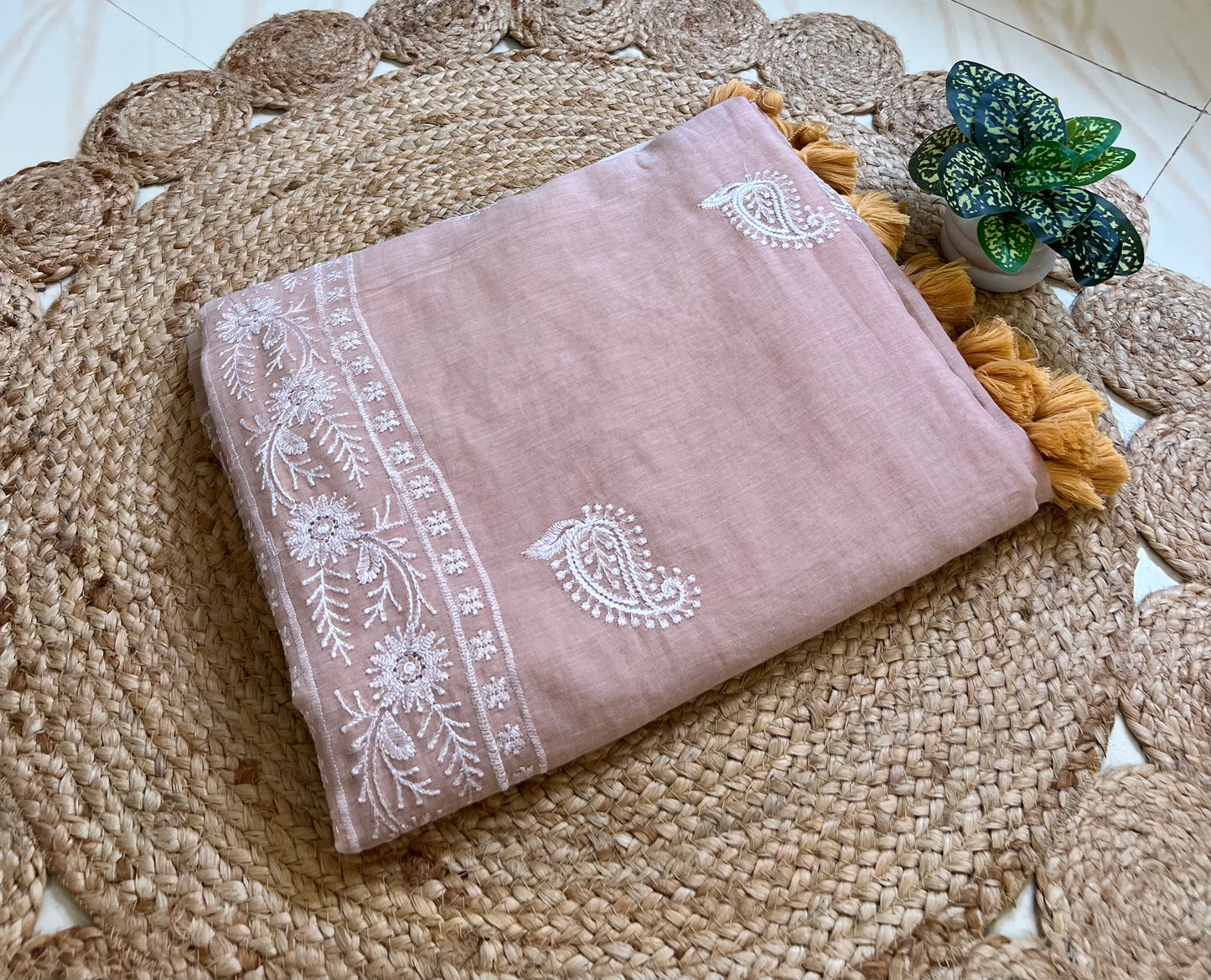 Dusty peach mul cotton saree with chikankari-style embroidery, neatly folded