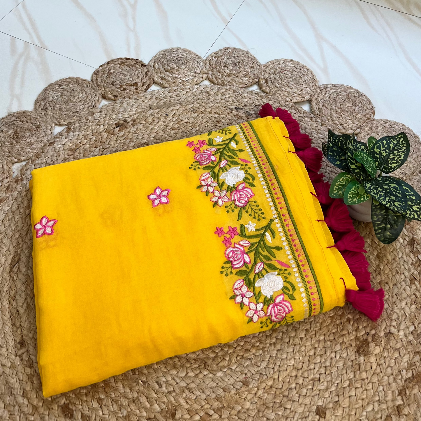 yellow mul cotton saree with pink and white floral embroidered border, neatly folded