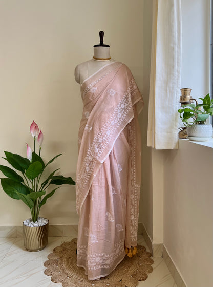 Dusty peach mul cotton saree with white chikankari-style embroidery, draped on a mannequin against a cream backdrop
