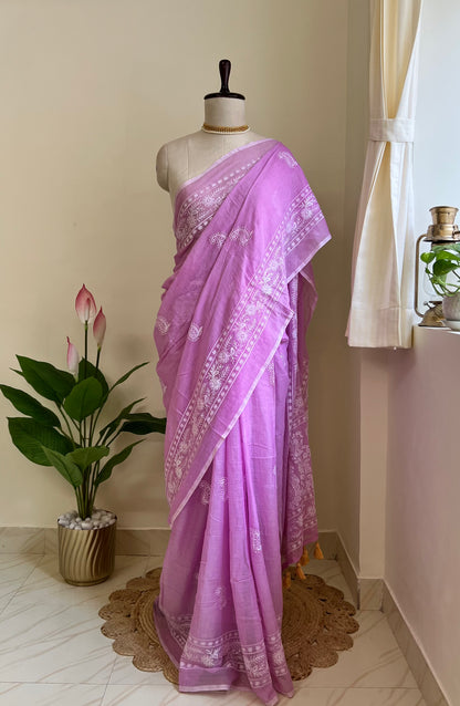 Lilac mul cotton saree with white chikankari-style embroidery, draped on a mannequin near a sunlit window