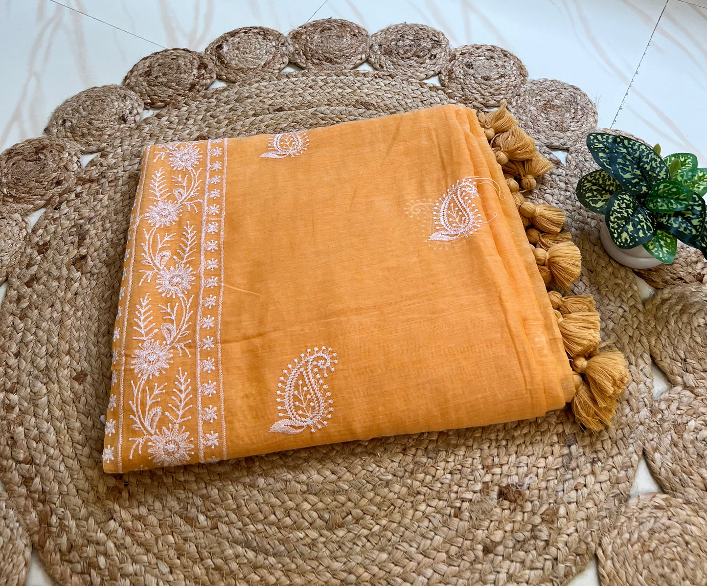 Marigold orange mul cotton saree with chikankari-style embroidery, neatly folded