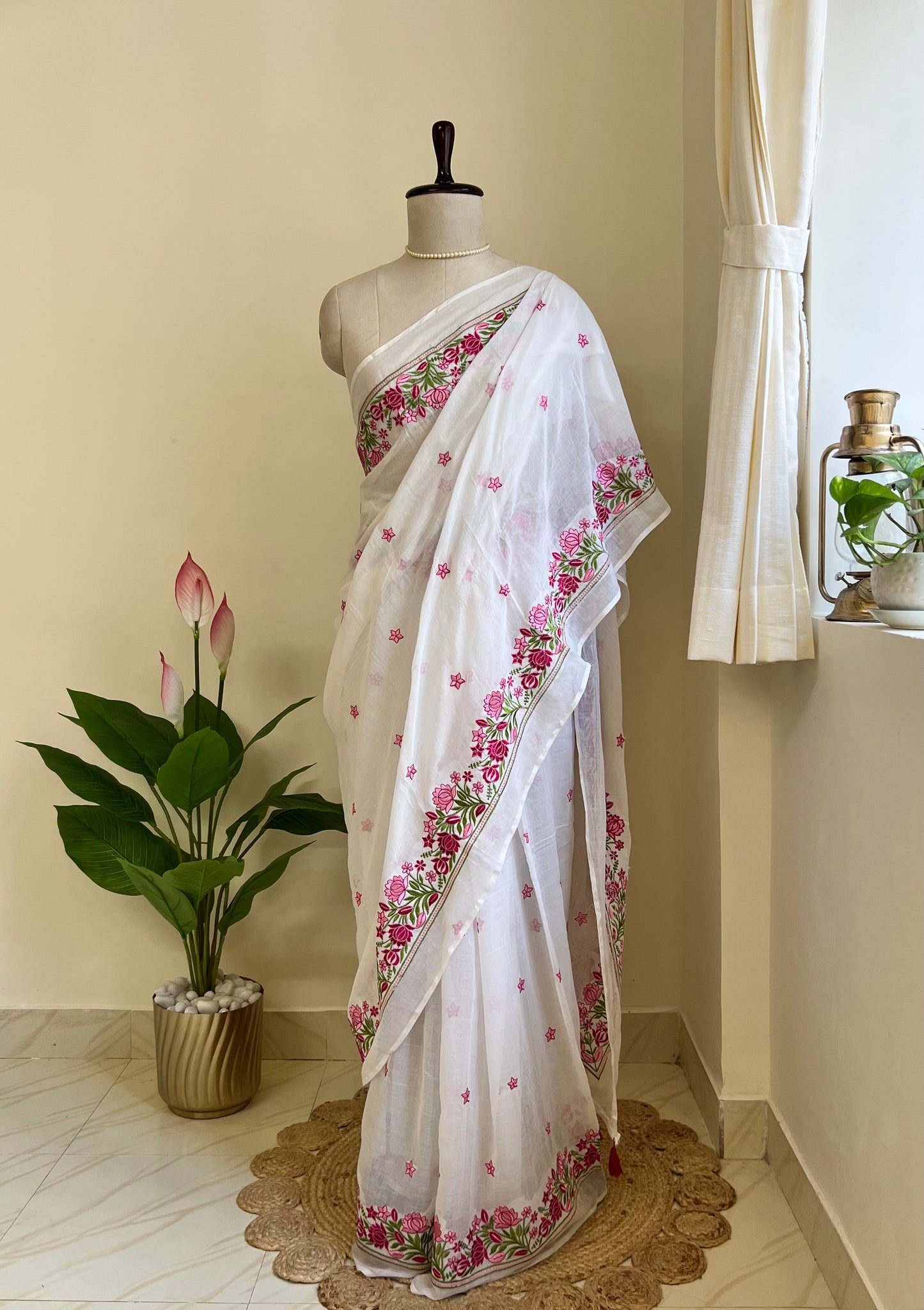 White mul cotton saree with pink and maroon floral hand-embroidered border, draped on mannequin