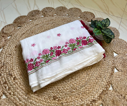 Folded white mul cotton saree showing pink and maroon floral embroidered border