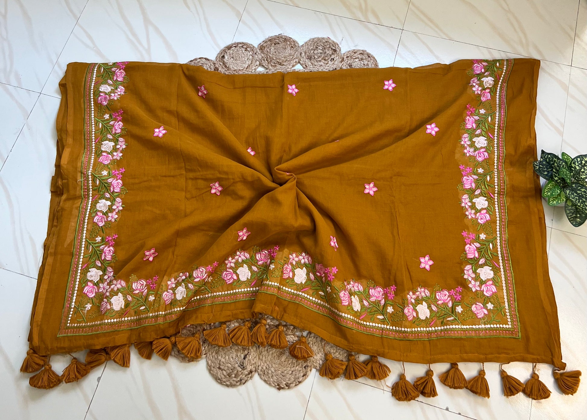 Close-up of pink hand-embroidered floral pallu border on mustard mul cotton saree