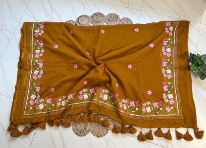 Close-up of pink hand-embroidered floral pallu border on mustard mul cotton saree
