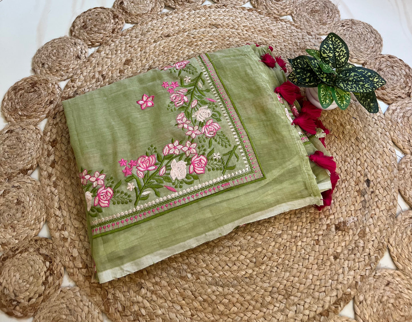 pista green mul cotton saree with pink floral embroidered border, neatly folded