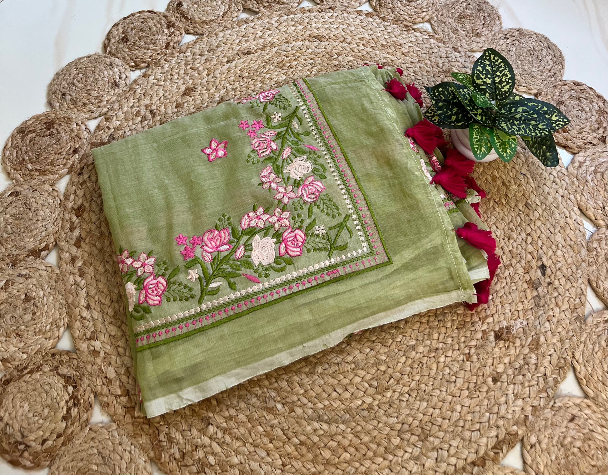 pista green mul cotton saree with pink floral embroidered border, neatly folded