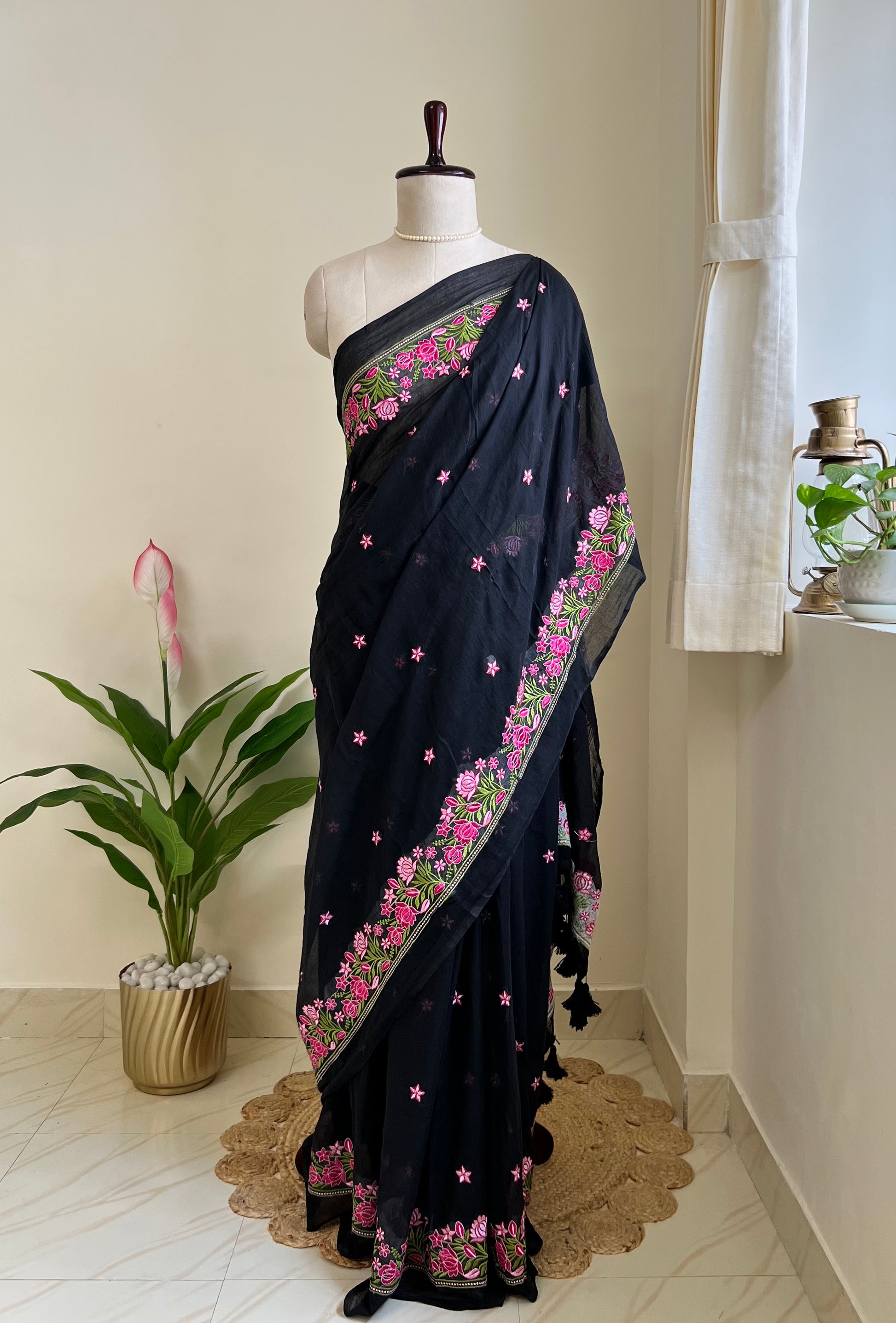 Black mul cotton saree with pink floral hand-embroidered border, draped on mannequin