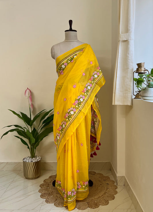 yellow mul cotton saree with pink and white embroidered floral border and tassel pallu, draped on a mannequin
