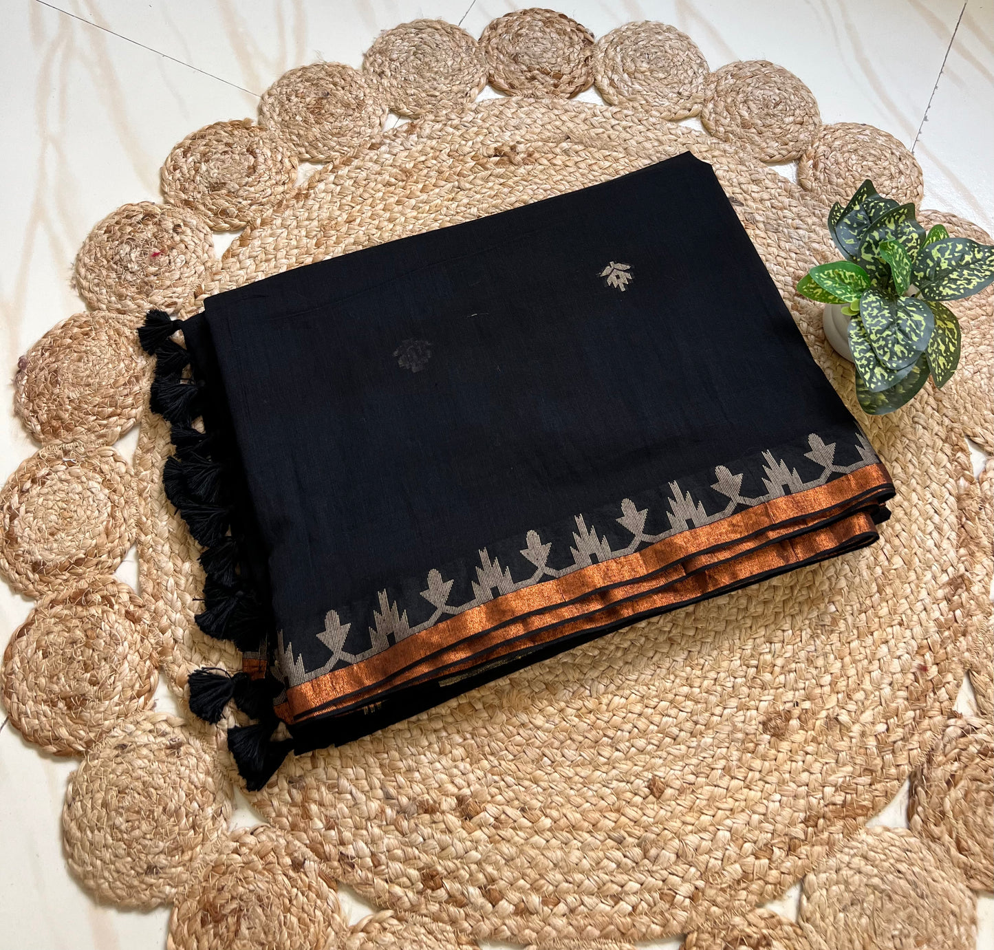 Folded black cotton jamdani saree showing woven border and motifs