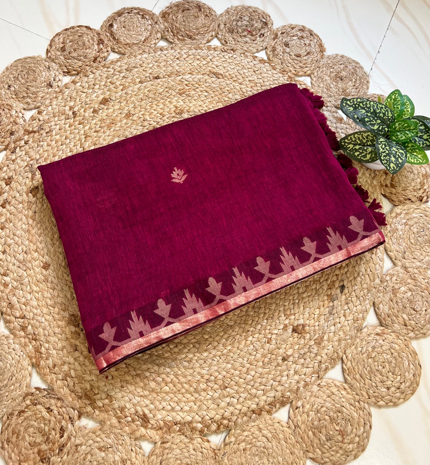 Folded berry wine cotton jamdani saree showing woven border and motifs